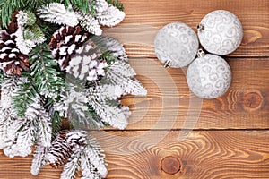 Christmas fir tree with snow and baubles on rustic wooden board