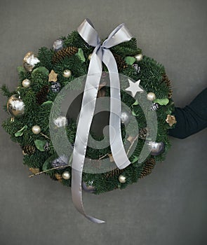 Christmas fir wreath in female hands on grey background