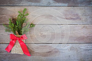 Christmas Firbranch with cones, red polka dot ribbon in the rustic bag on old wooden background