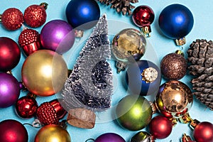 Christmas flat lay with colorful christmas balls, little christmas tree and a pine cone