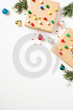 Christmas flat lay composition with craft paper gift boxes decorated with colorful balls and Christmas tree toys on white