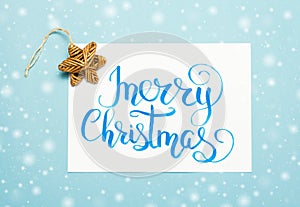 Christmas flat lay: lettering text `Merry Christmas` and vintage wooden star on blue background.