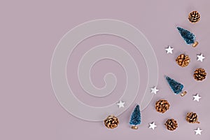 Christmas flat lay with small Christmas trees, pine cones and wooden star ornaments in corner of gray background