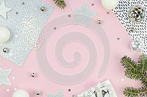 Christmas flat lay styled scene - top view frame with evergreen tree twigs and christmas decorations. Pink background