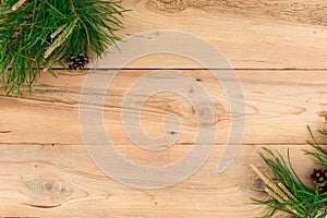 Christmas flatlay on a rustic wooden background: green pine needles with cones.