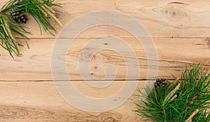 Christmas flatlay on a rustic wooden background: green pine needles with cones.