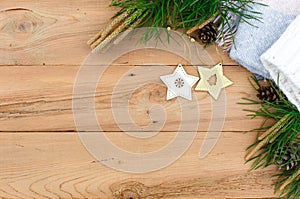 Christmas flatlay on a rustic wooden background: green pine needles with cones, wooden decorations in the shape of stars,