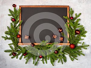 Christmas flatly copyspace. A chalkboard surrounded by spruce twigs and Christmas toys on a grey background. Holiday card, copy