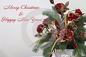 A Christmas Flower Bouquet off Fancy Red Flowers with Merry Christmas and Happy New Year with some Christmas Tree Branches.