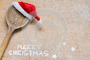 Christmas food background with spoon, Santa Claus hat and flour. Merry Christmas inscription