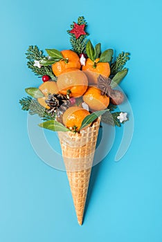 Christmas food concept. tangerine fruits, fir tree branches and Christmas decorations in waffle ice cream cone