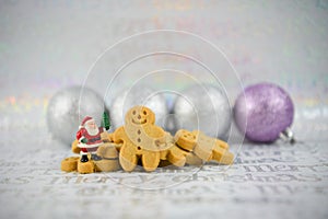 Christmas food photography gingerbread man mini santa claus and silver tree baubles on xmas wrapping paper background