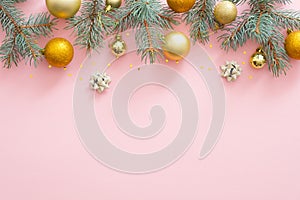 Christmas frame border made of fir tree branches, golden balls, confetti on pastel pink background. Flat lay, top view, copy space