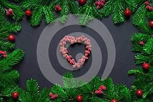 Christmas frame border wirh fir branch, berry heart and baubles on black background