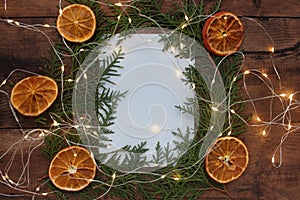 Christmas frame with Christmas tree branches, blank note white paper, dried orange ornaments, and garland
