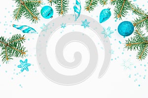 Christmas frame of fir branch, blue decoration and snowflake on white background. Flat lay, top view