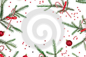 Christmas frame of fir branches and red decoration on white background. Flat lay