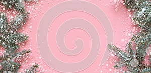 Christmas frame of fir branches, snowy white decorations on pink table. Xmas background. Flat lay. Top view with copy space