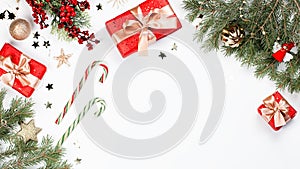 Christmas frame flat lay with pine, red presents, golden elements, candy canes, confetti. Christmas template on white background.