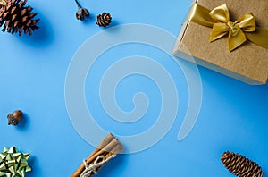 Christmas frame with gift box, conifer cones, cinnamon and ornaments on blue paper background with copy space