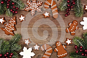 Christmas frame of gingerbread cookies and tree branches, top view on a rustic wood background