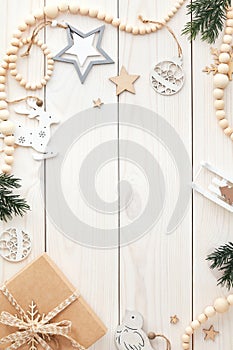 Christmas frame, greeting card. White wooden desk table with gift box, vintage decorations, wooden garland, fir branches. Happy