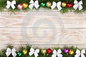 Christmas frame made of fir branches decorated with balls and bows on a light wooden background
