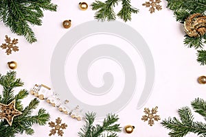 Christmas frame made of fir branches, gold decorations and toy train on white background