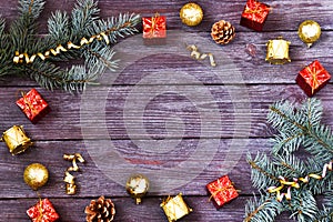 Christmas frame made of fir branches, holiday decorations and pine cones on a wooden table