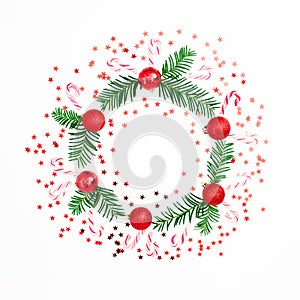 Christmas frame made of fir branches and red balls decoration with confetti on white background. Festive background. Flat lay, top