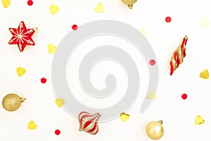 Christmas frame made of golden and red decorations with confetti on white background. Flat lay, top view, copy space