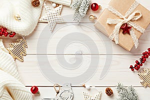 Christmas frame made of vintage Christmas decorations, knitted sweater, red berries, fir branches on white wooden desk table.