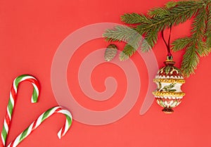 Christmas frame on red background. Green fir branches, Xmas decoration and candy canes. Top view, flat lay. Copy space