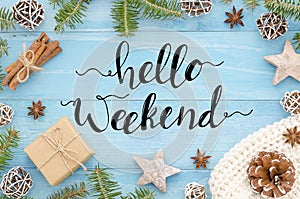 Hello weekend hand lettering on blue wooden background christmas tree, cinnamone,anice star, pine cones and fir tree photo