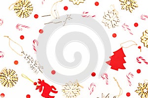 Christmas frame with wooden tree decoration, snowflakes and candy canes on white background. Flat lay, top view. New Year concept.