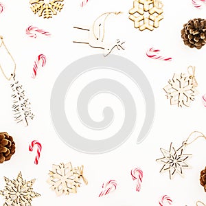 Christmas frame with wooden tree decoration, snowflakes and pine cones on white background. Flat lay, top view. New Year concept.