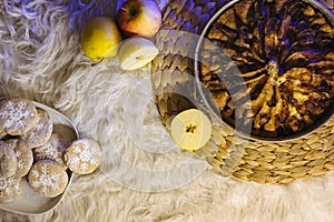 Christmas fruit cake on a table with white fur and apples from top view