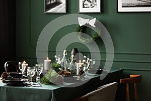 Christmas garland and black and white posters on green wall of dining room set for christmas dinner