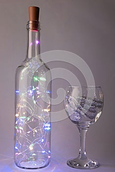 christmas garland in a bottle with a glass on a gray background