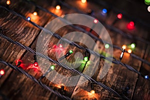 Christmas garland of colorful light bulbs on an dark old weathered vintage table or wooden brown board. Christmas decoration, New