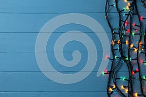 Christmas garland lights on blue background, copy space.