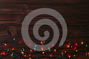 Christmas garland lights on brown background, copy space.