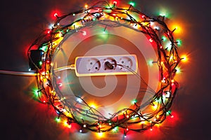 Christmas garland lights circle around electric extension cord
