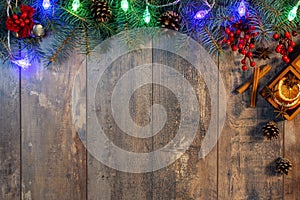 Christmas garland lights and decoration on wooden background. Christmas fir tree with decoration on dark wooden board. Border art