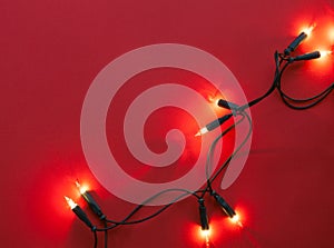 Christmas garland lights on red paper background. Top view