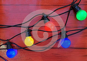 Christmas garland with multi-colored light bulbs on a brown background