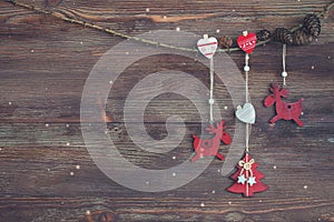 Christmas Garland with red wooden deer, hearts, Christmas-tree and cones. Dark background. Snowflakes.