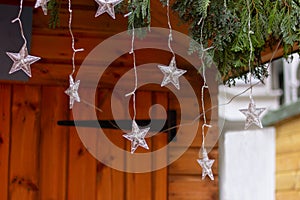 Christmas garland and star lights on the roof of a wooden house. winter and New Year festive decoration of the streets