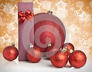 Christmas gift and baubles on golden background