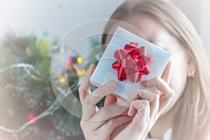 Christmas gift. Blurred Woman in white sweater holding gift box in front of face. Faceless. New year and holidays concept.